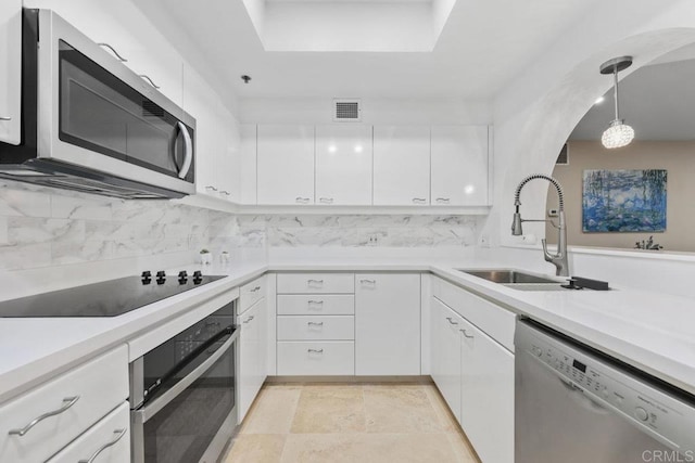 kitchen featuring appliances with stainless steel finishes, a sink, white cabinetry, and backsplash