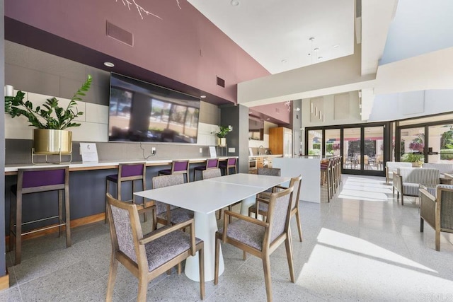 dining space featuring a towering ceiling and dark speckled floor