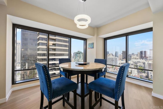 dining space with wood finished floors, a chandelier, baseboards, and a view of skyline