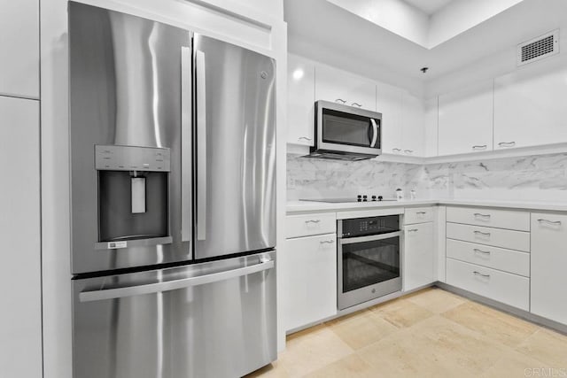 kitchen featuring stainless steel appliances, white cabinets, light countertops, and tasteful backsplash