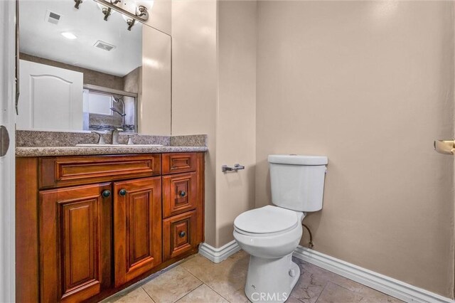bathroom featuring baseboards, vanity, and toilet