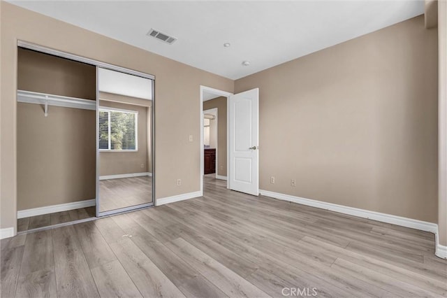 unfurnished bedroom with baseboards, wood finished floors, and a closet