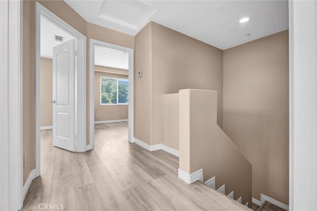 corridor with an upstairs landing, light wood-style floors, baseboards, and recessed lighting