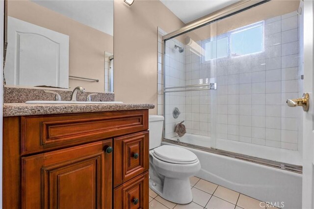 full bath with toilet, tile patterned flooring, vanity, and shower / bath combination with glass door