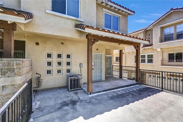 back of property featuring a tiled roof and stucco siding