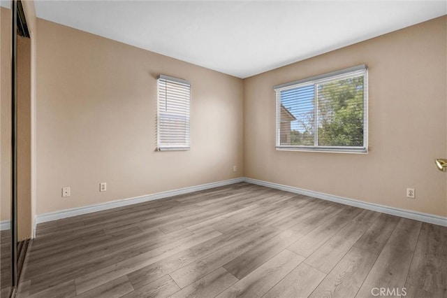 spare room with wood finished floors, healthy amount of natural light, and baseboards