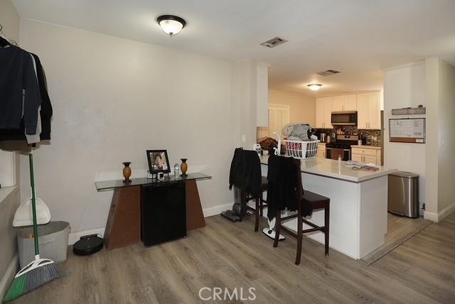 885 N Millard Ave, Rialto, CA 92376 - kitchen featuring stainless steel appliances, light wood finished floors, a kitchen breakfast bar, a peninsula, and white cabinets