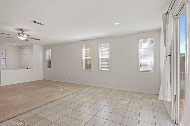 empty room with healthy amount of natural light, light colored carpet, recessed lighting, light tile patterned flooring, and ceiling fan