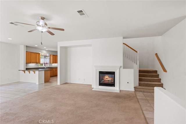 unfurnished living room featuring ceiling fan, light tile patterned floors, a glass covered fireplace, stairway, and recessed lighting
