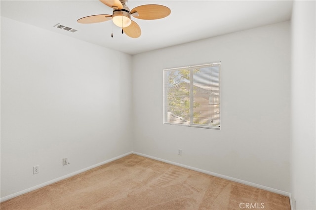 spare room featuring light colored carpet, baseboards, and ceiling fan