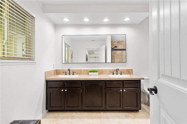 bathroom featuring double vanity, baseboards, and a tile shower