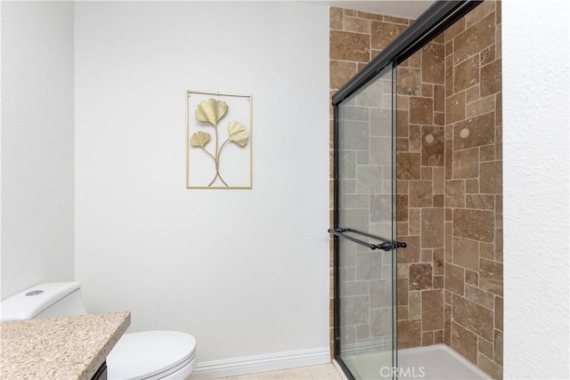 bathroom with a stall shower, toilet, vanity, and baseboards