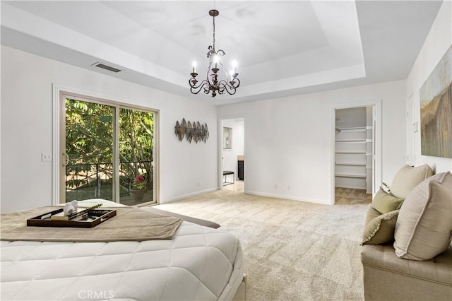 bedroom with a tray ceiling, a chandelier, access to exterior, a spacious closet, and light carpet