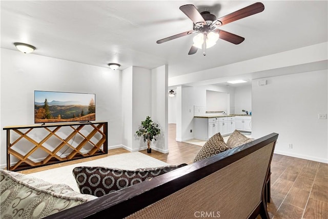 living area with wood finished floors, baseboards, and ceiling fan