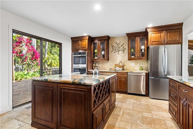 kitchen featuring appliances with stainless steel finishes, stone tile floors, a sink, tasteful backsplash, and recessed lighting