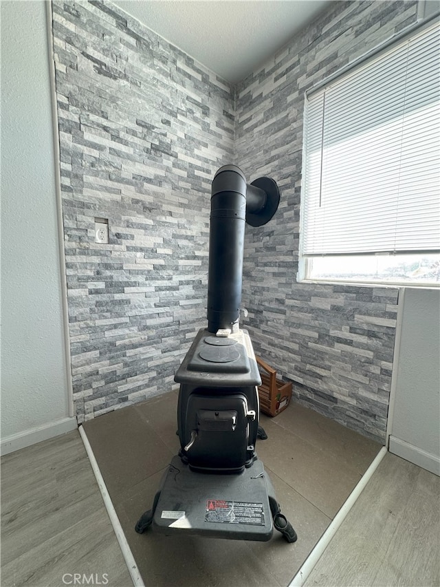 detailed view of a wood stove, wood finished floors, and baseboards