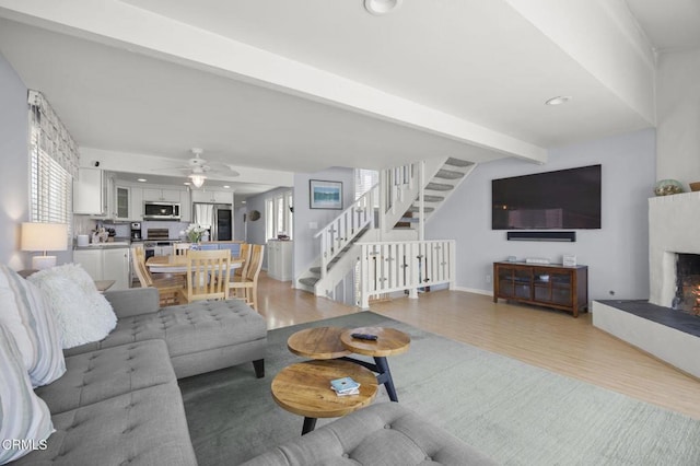 325 Ocean Dr, Oxnard, CA 93035 - living area with stairs, a warm lit fireplace, light wood finished floors, healthy amount of natural light, and beamed ceiling