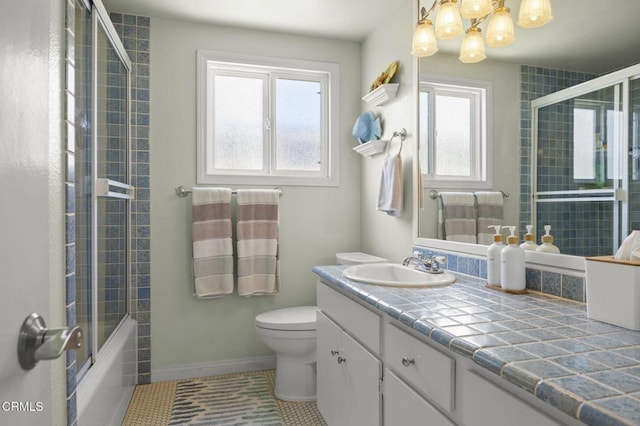 325 Ocean Dr, Oxnard, CA 93035 - bathroom featuring tile patterned flooring, vanity, toilet, baseboards, and bath / shower combo with glass door