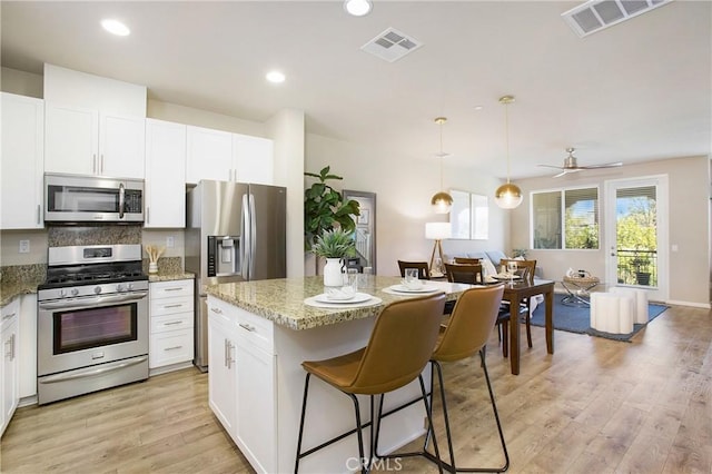 2651 W Lincoln Ave Unit 40, Anaheim, CA 92801 - kitchen with stainless steel appliances, open floor plan, a center island, light wood finished floors, and white cabinetry