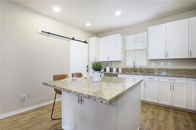 2651 W Lincoln Ave Unit 40, Anaheim, CA 92801 - kitchen with a breakfast bar area, white cabinetry, light wood-style floors, a center island, and recessed lighting