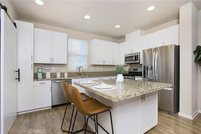2651 W Lincoln Ave Unit 40, Anaheim, CA 92801 - kitchen featuring appliances with stainless steel finishes, a center island, white cabinetry, a breakfast bar, and light wood finished floors