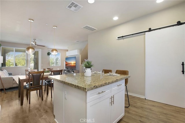 2651 W Lincoln Ave Unit 40, Anaheim, CA 92801 - kitchen with a barn door, light wood-style flooring, white cabinets, a kitchen island, and recessed lighting