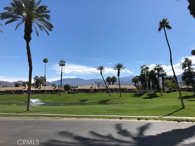 view of community with a yard, view of golf course, and a water and mountain view