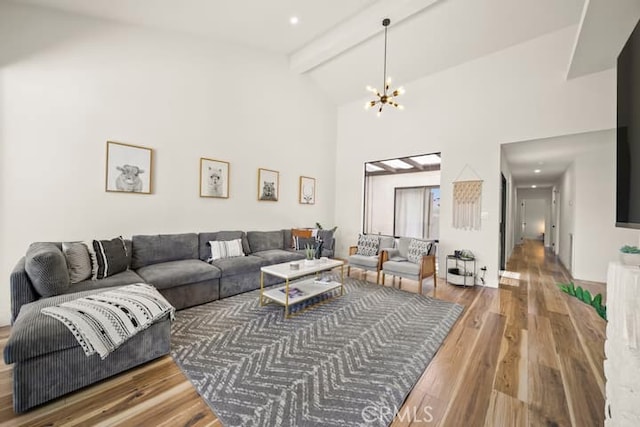 living area featuring wood finished floors, a chandelier, beam ceiling, and high vaulted ceiling
