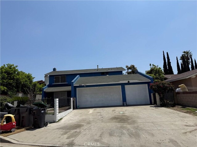 view of front of house with fence, concrete driveway, and a garage