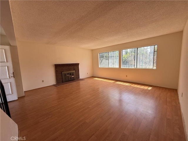 unfurnished living room featuring wood finished floors, a textured ceiling, and a fireplace