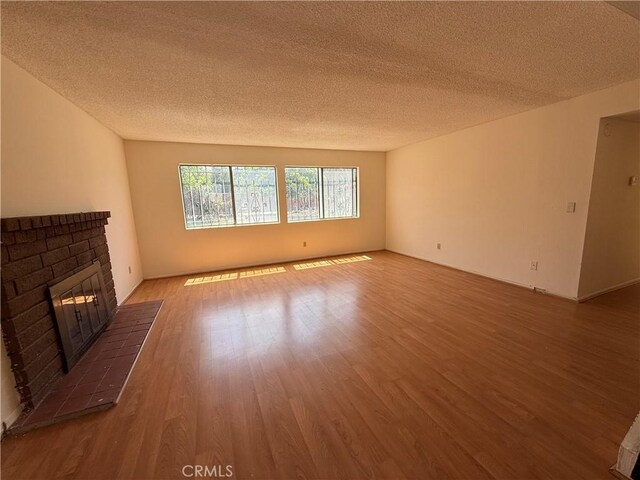 unfurnished living room with a textured ceiling, a fireplace, and wood finished floors