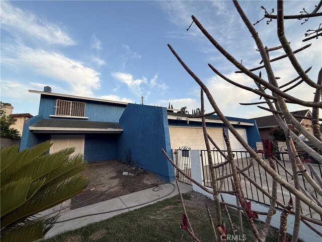 rear view of property featuring fence and a garage