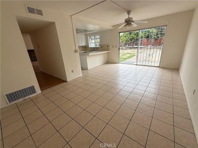 unfurnished living room featuring ceiling fan, light tile patterned flooring, and baseboards