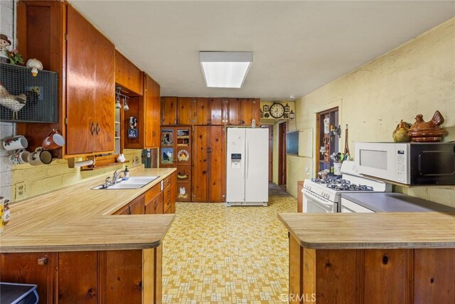 2831 Foothill Blvd, Oroville, CA 95966 - kitchen with white appliances, a sink, light flooring, a peninsula, and brown cabinets