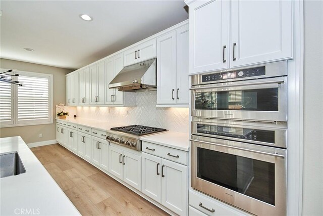 223 Gaspar, Irvine, CA 92618 - kitchen featuring under cabinet range hood, light wood finished floors, light countertops, decorative backsplash, and appliances with stainless steel finishes