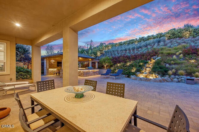 patio terrace at dusk with outdoor dining space and a gazebo