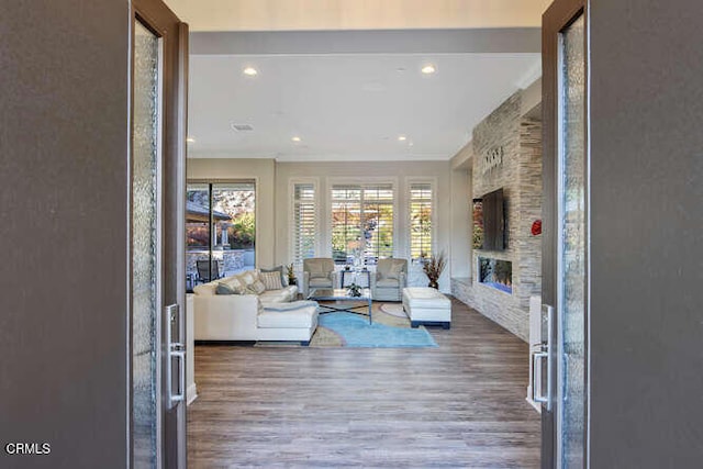 living room featuring wood finished floors, crown molding, a fireplace, and recessed lighting