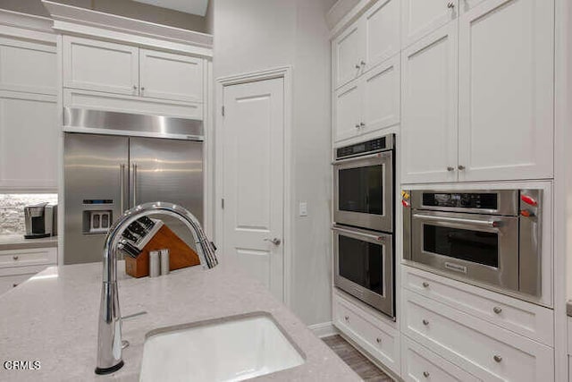 kitchen featuring stainless steel appliances, a sink, and white cabinets