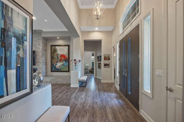 foyer entrance featuring a chandelier, crown molding, dark wood-type flooring, baseboards, and a towering ceiling