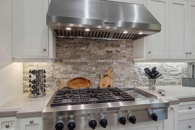 kitchen featuring ventilation hood, stainless steel gas cooktop, white cabinets, and light countertops