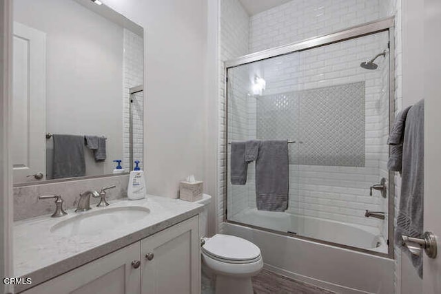 bathroom featuring bath / shower combo with glass door, vanity, and toilet