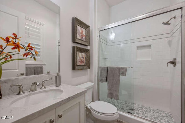 full bathroom featuring a shower stall, toilet, and vanity
