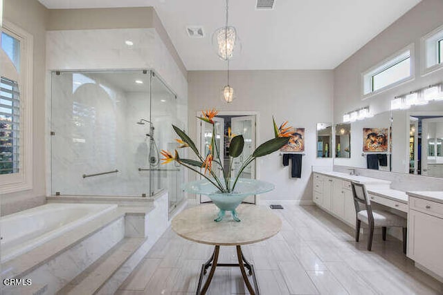 bathroom featuring a garden tub, vanity, a stall shower, and a chandelier