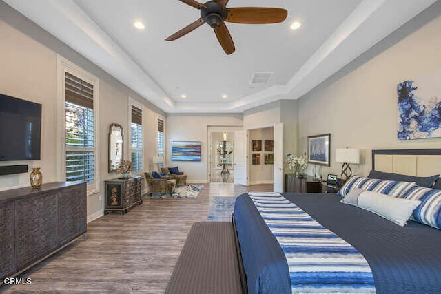 bedroom featuring a tray ceiling, recessed lighting, wood finished floors, and baseboards