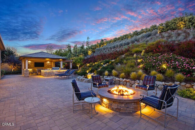 patio terrace at dusk featuring a gazebo and a fire pit