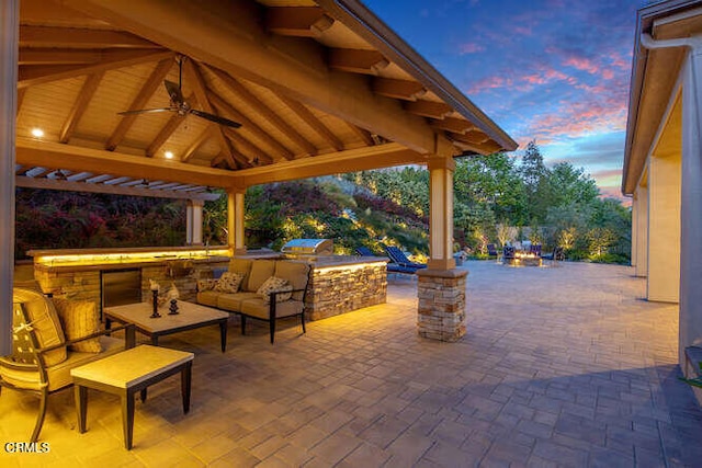 patio terrace at dusk with a gazebo, area for grilling, and ceiling fan