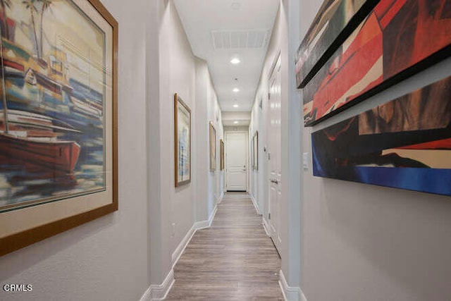 corridor featuring wood finished floors, baseboards, recessed lighting, and attic access