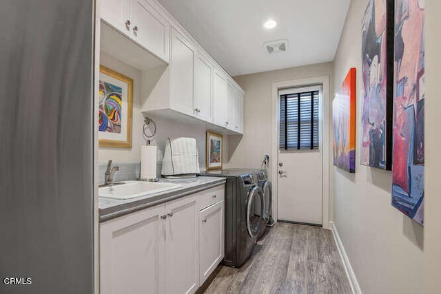 laundry room with independent washer and dryer, light wood-style flooring, cabinet space, baseboards, and recessed lighting