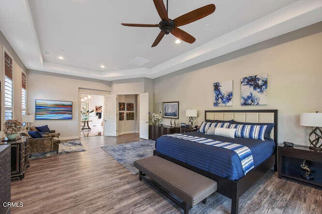 bedroom featuring a raised ceiling, wood finished floors, recessed lighting, baseboards, and a ceiling fan
