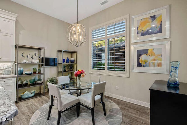 dining room featuring wood finished floors, a chandelier, and baseboards